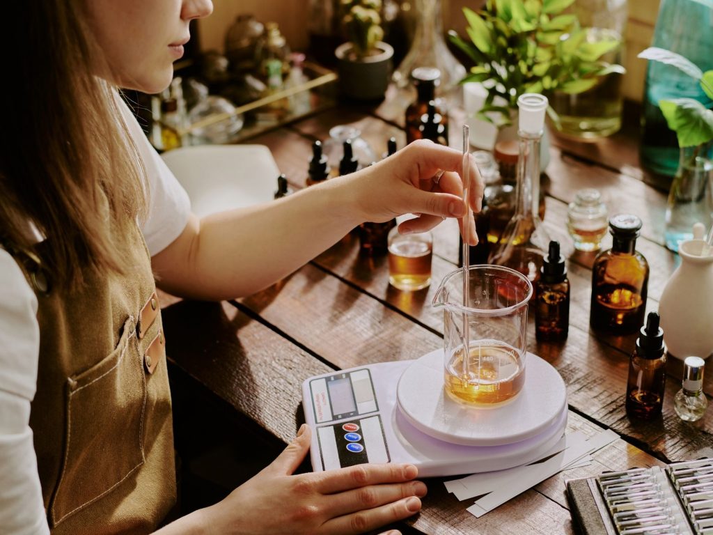 An artisan creating natural fragrances using natural essential oils, absolutes, resins, CO2 extracts, or fragrance molecules blended with alcohol, or blended with carrier oil