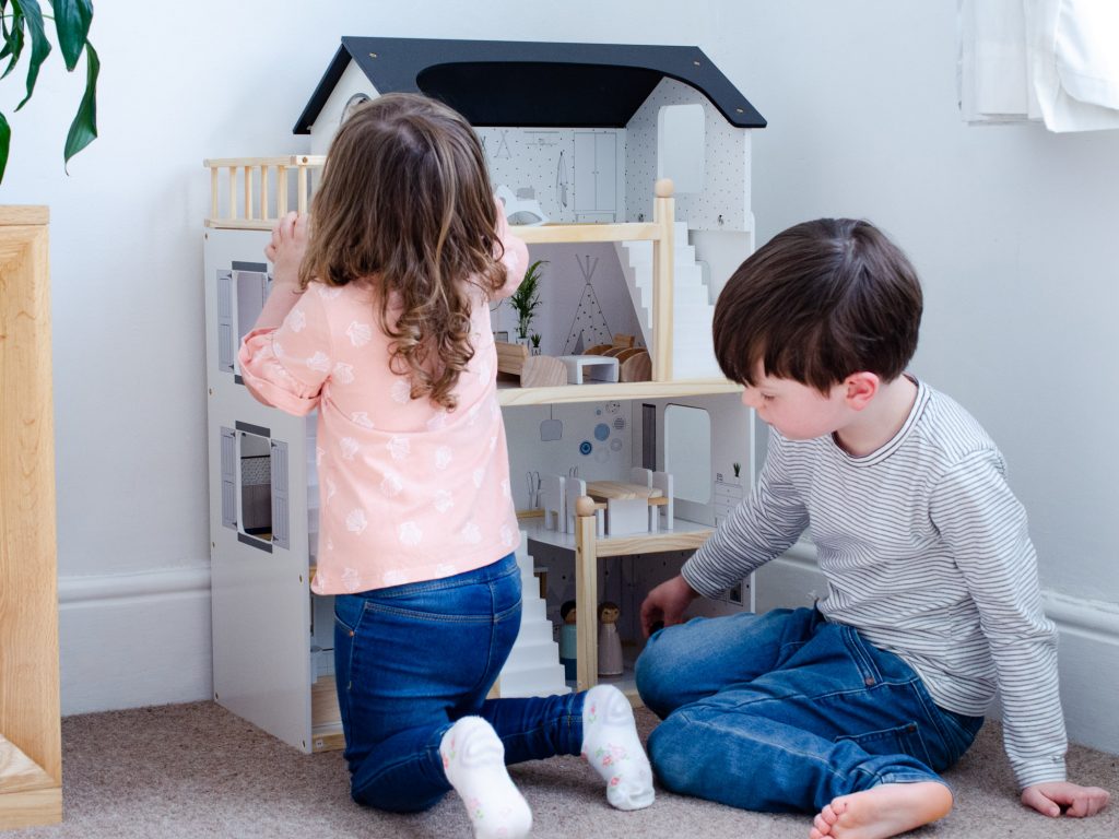 Both children enjoy the wooden dolls house