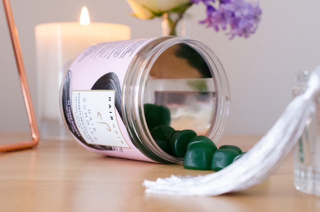 Hair Gain Gummies spilling from their jar
