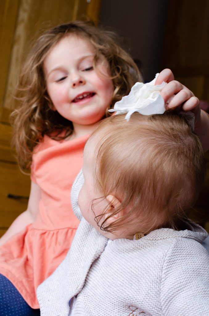 Cara cleaning Lydia's head with a wet wipe
